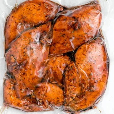 Marinated balsamic chicken ready for grilling with fresh herbs