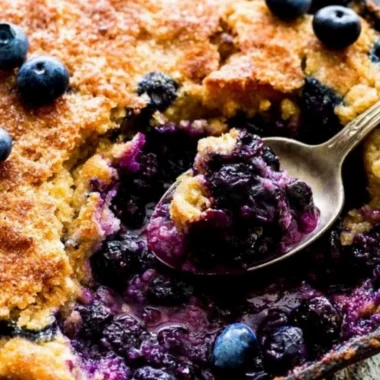 Delicious homemade blueberry cobbler topped with golden crust and fresh berries