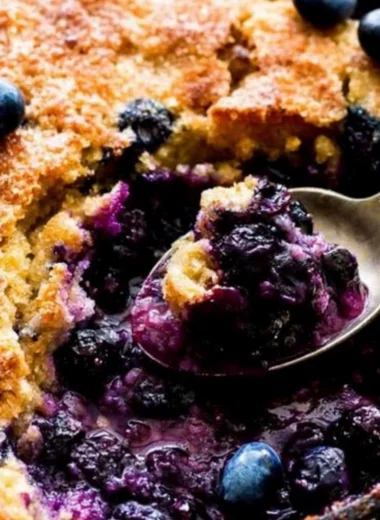Delicious homemade blueberry cobbler topped with golden crust and fresh berries