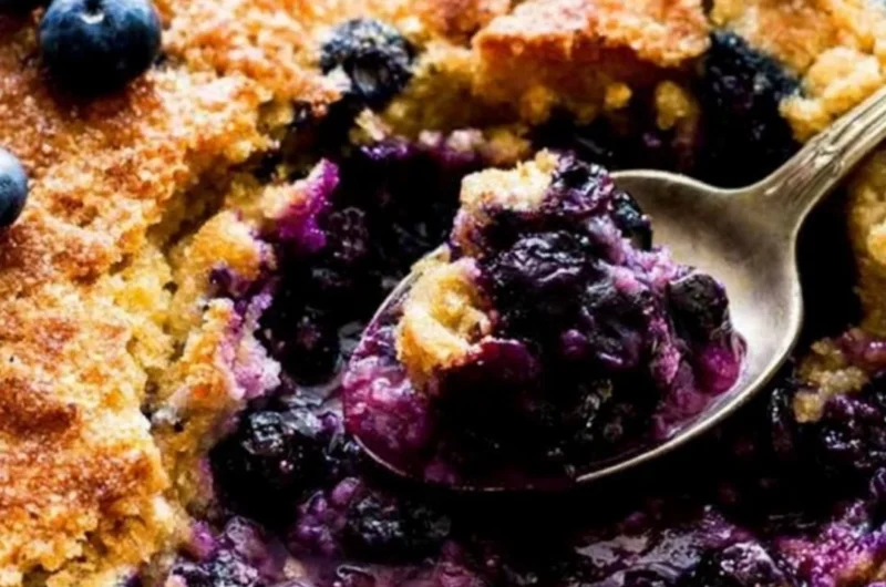Delicious homemade blueberry cobbler topped with golden crust and fresh berries