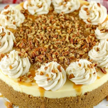 Slice of browned butter pecan cheesecake on a plate with pecans on top