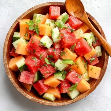 Easy melon salad with honey lime dressing in a bowl, garnished with mint leaves.