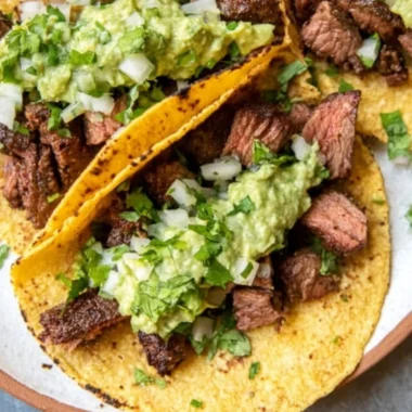 Grilled steak tacos topped with avocado salsa on a plate