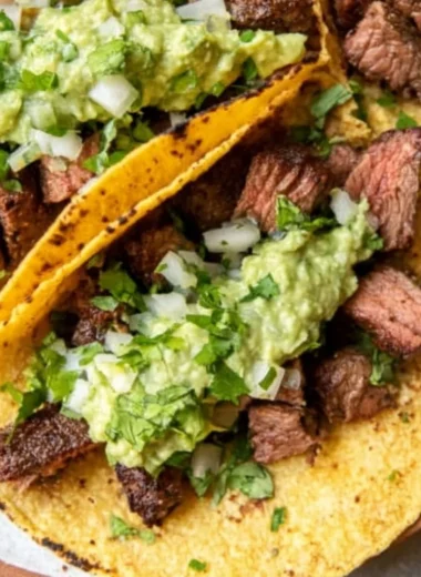 Grilled steak tacos topped with avocado salsa on a plate