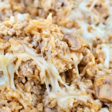 Ground turkey skillet casserole topped with cheese and vegetables.
