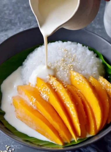 Delicious plate of Mango Sticky Rice topped with ripe mango slices and coconut sauce