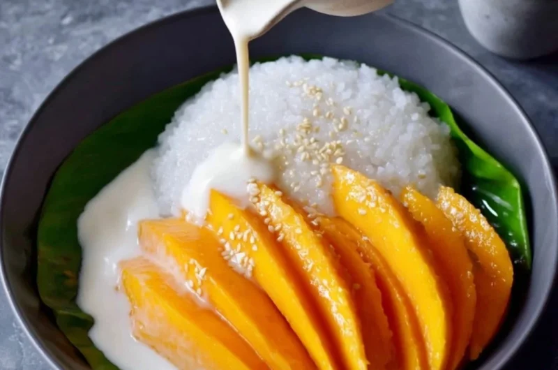 Delicious plate of Mango Sticky Rice topped with ripe mango slices and coconut sauce