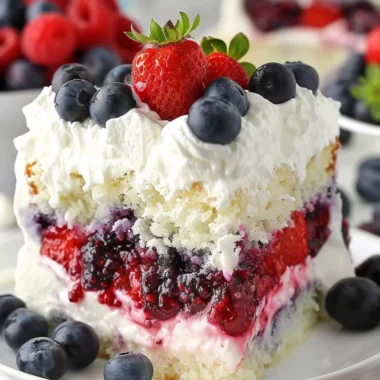 Delicious Summer Berry Poke Cake topped with fresh berries and whipped cream