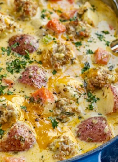 Creamy sausage potato soup served in a bowl with fresh herbs