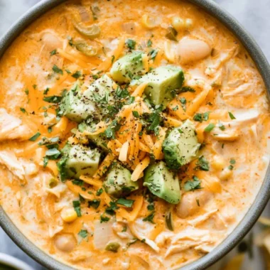 Bowl of cozy creamy white chicken chili topped with cilantro and tortilla strips.