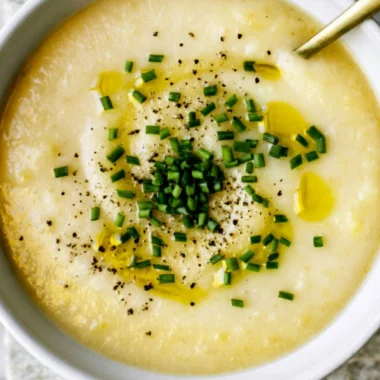 Bowl of creamy potato leek soup garnished with fresh herbs