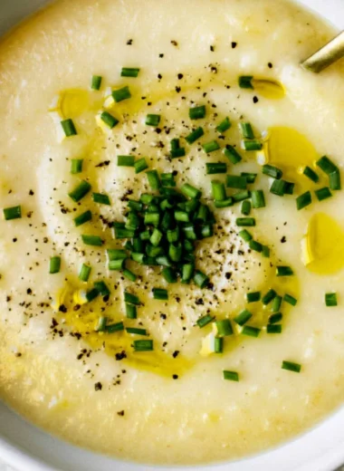 Bowl of creamy potato leek soup garnished with fresh herbs