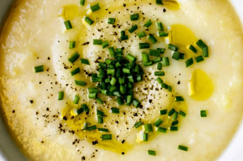 Bowl of creamy potato leek soup garnished with fresh herbs