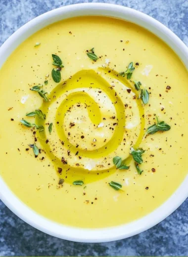 Bowl of creamy summer squash soup garnished with herbs
