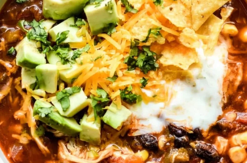 Bowl of Crockpot Chicken Enchilada Soup garnished with cilantro and avocado