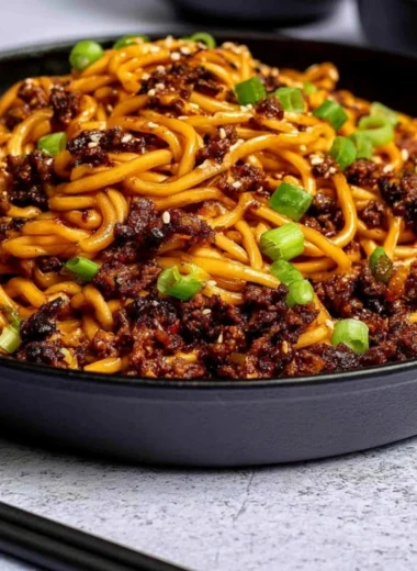 Bowl of Mongolian ground beef noodles garnished with vegetables