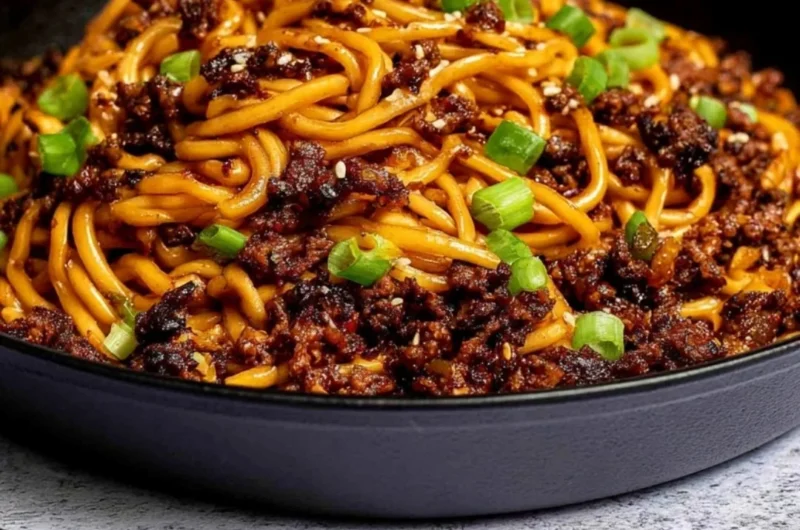 Bowl of Mongolian ground beef noodles garnished with vegetables