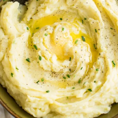 Bowl of perfect creamy mashed potatoes with butter and herbs